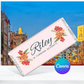 Chocolate bar with floral design and text Riley is turning seventy! against a cityscape background