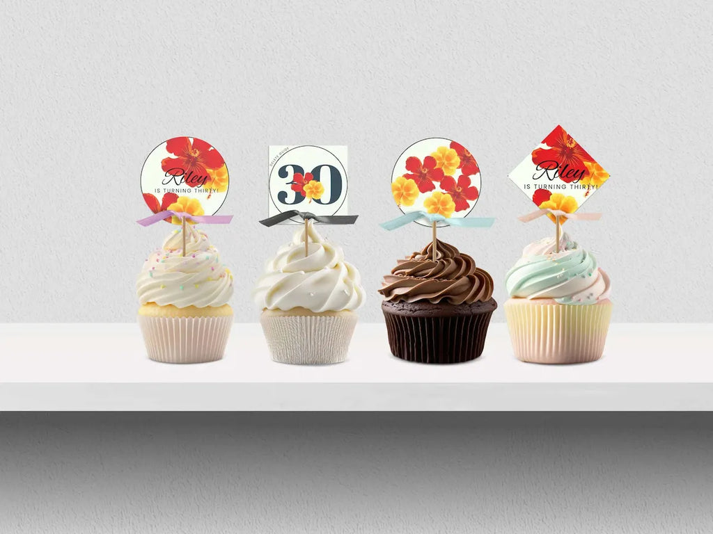 Four cupcakes with decorative toppers on a white surface