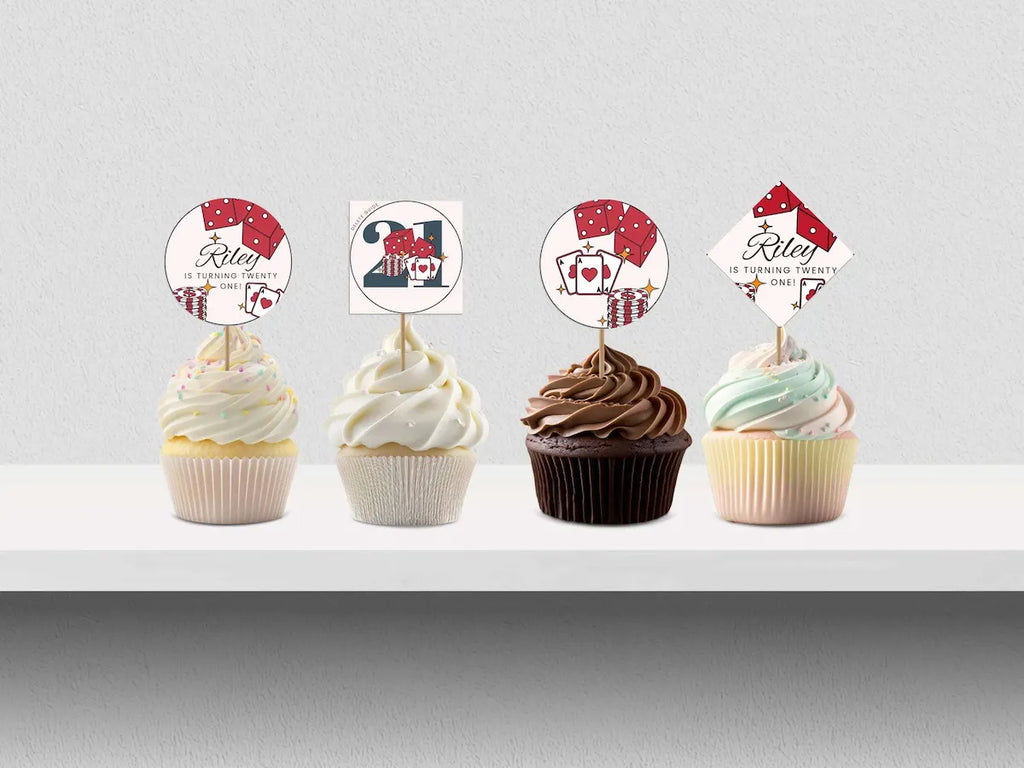 Four cupcakes with decorative toppers on a white surface