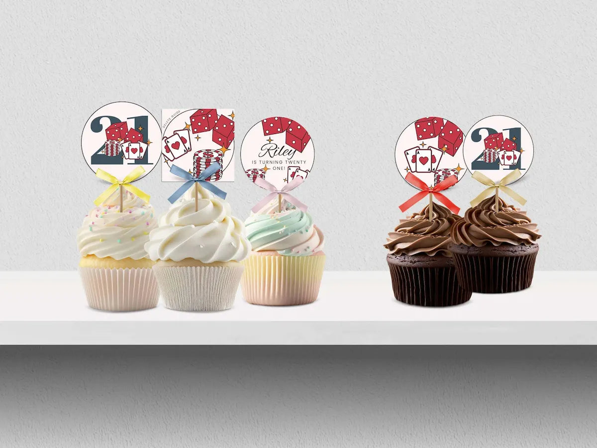 Two sets of 21st birthday cupcake toppers displayed on cupcakes. The left set features pastel-colored toppers with a '21' and playing card graphics, tied with pastel ribbons on white-frosted cupcakes.