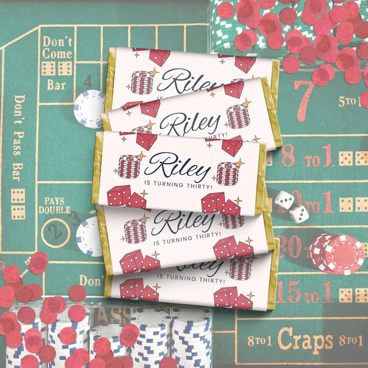 Three personalized chocolate favor bags with a casino-themed design featuring red dice, red chips, and gold borders, laid out on a green craps table with scattered red confetti and dice.