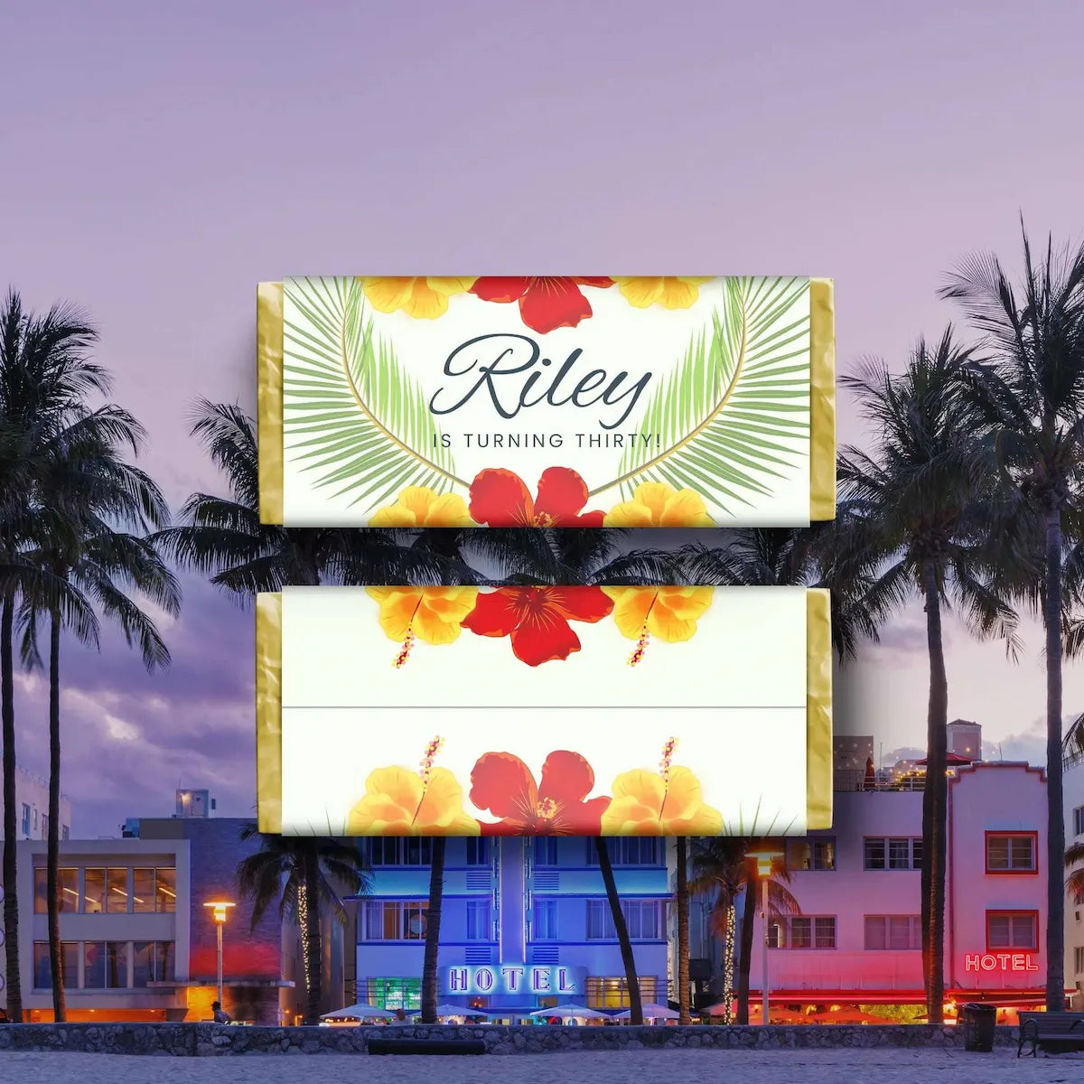 Two rectangular tropical-themed birthday cake toppers stacked vertically, featuring the text 'Riley IS TURNING THIRTY' with red hibiscus flowers and yellow-orange flowers on a white background with green palm leaves. The background shows a beach resort scene at dusk with palm trees and a hotel.